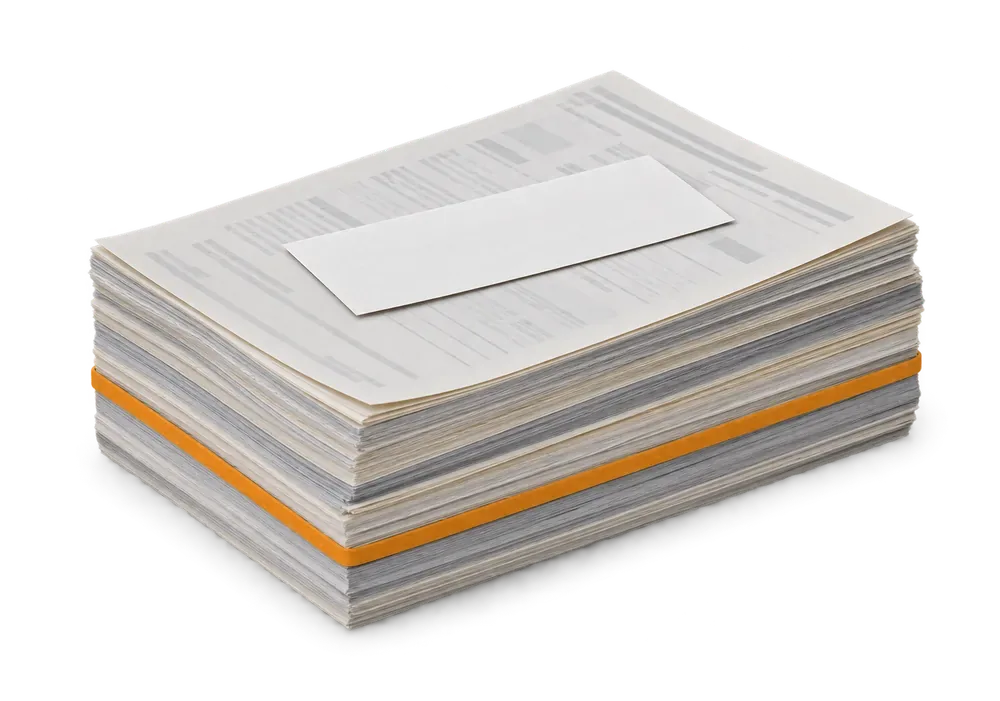 One small blank slip resting alone on a thick banded stack of statement pages
